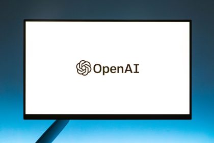 Logo da OpenAI exibido em um monitor diante de um fundo azul em degradê
