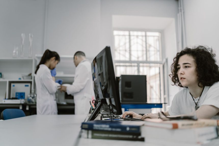Pesquisadora trabalha em um computador em um laboratório acadêmico de computação.