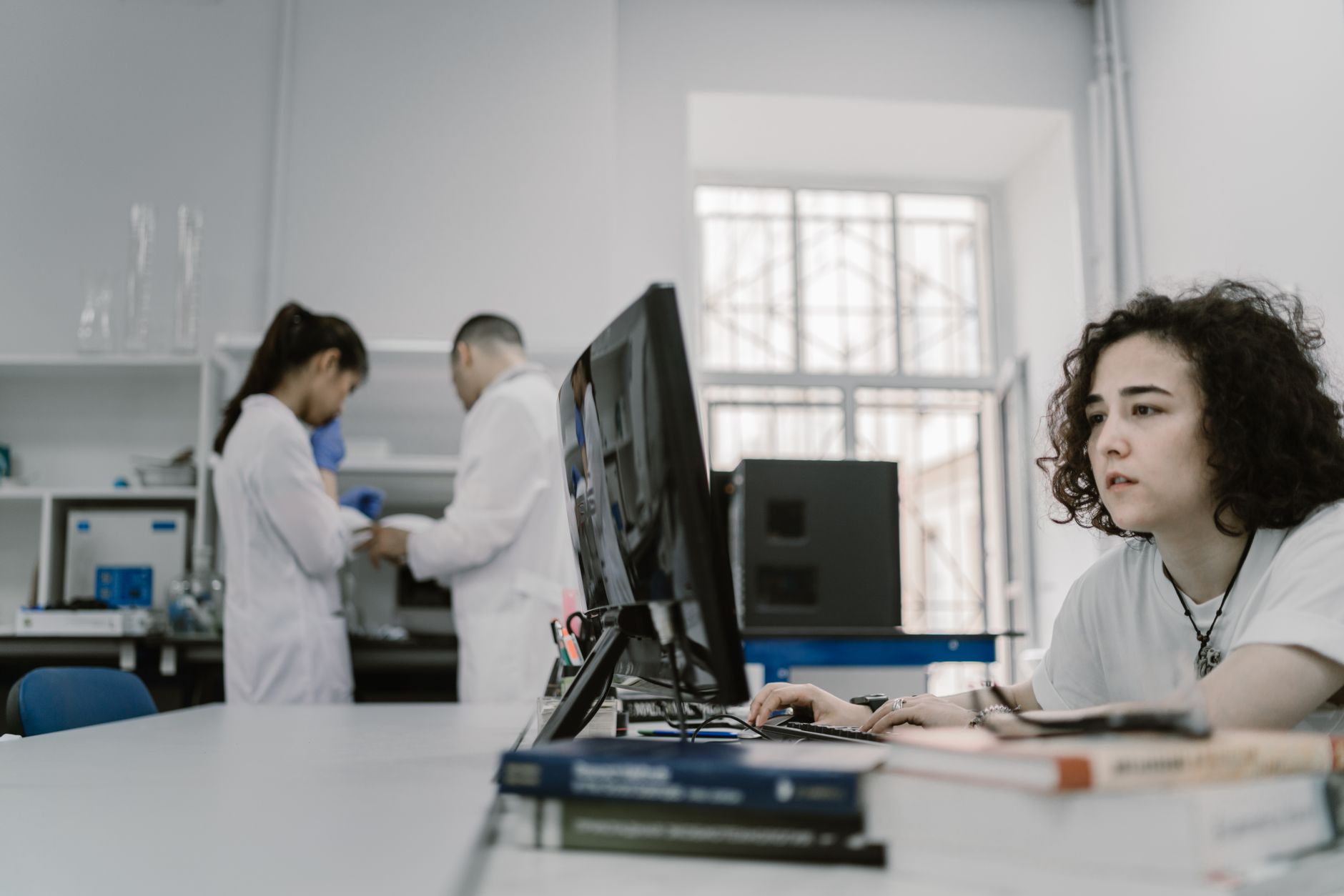Pesquisadora trabalha em um computador em um laboratório acadêmico de computação.
