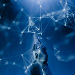 Mão robótica interage com uma rede digital azul, em representação abstrata de inteligência artificial e tecnologia.