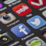Smartphone exibindo ícones de aplicativos e redes sociais na tela.